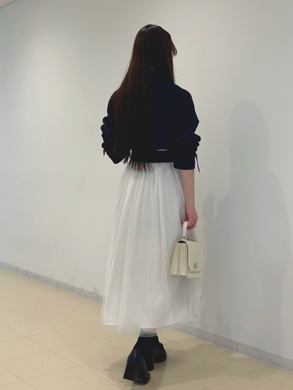 ブラック系のブーツ、ホワイト系のハンドバッグ、ホワイト系のニット/セーターを着用したレディースの春コーディネートの4枚目の写真