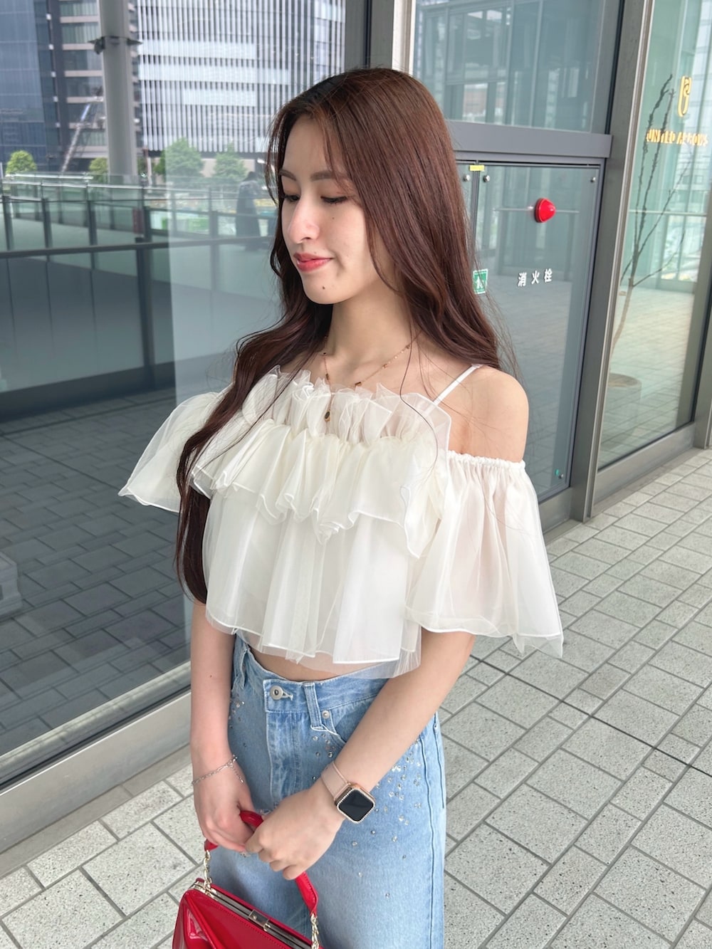 レッド系のハンドバッグ、ホワイト系のシャツ/ブラウス、ブルー系のデニムパンツを着用したレディースの春コーディネートの4枚目の写真