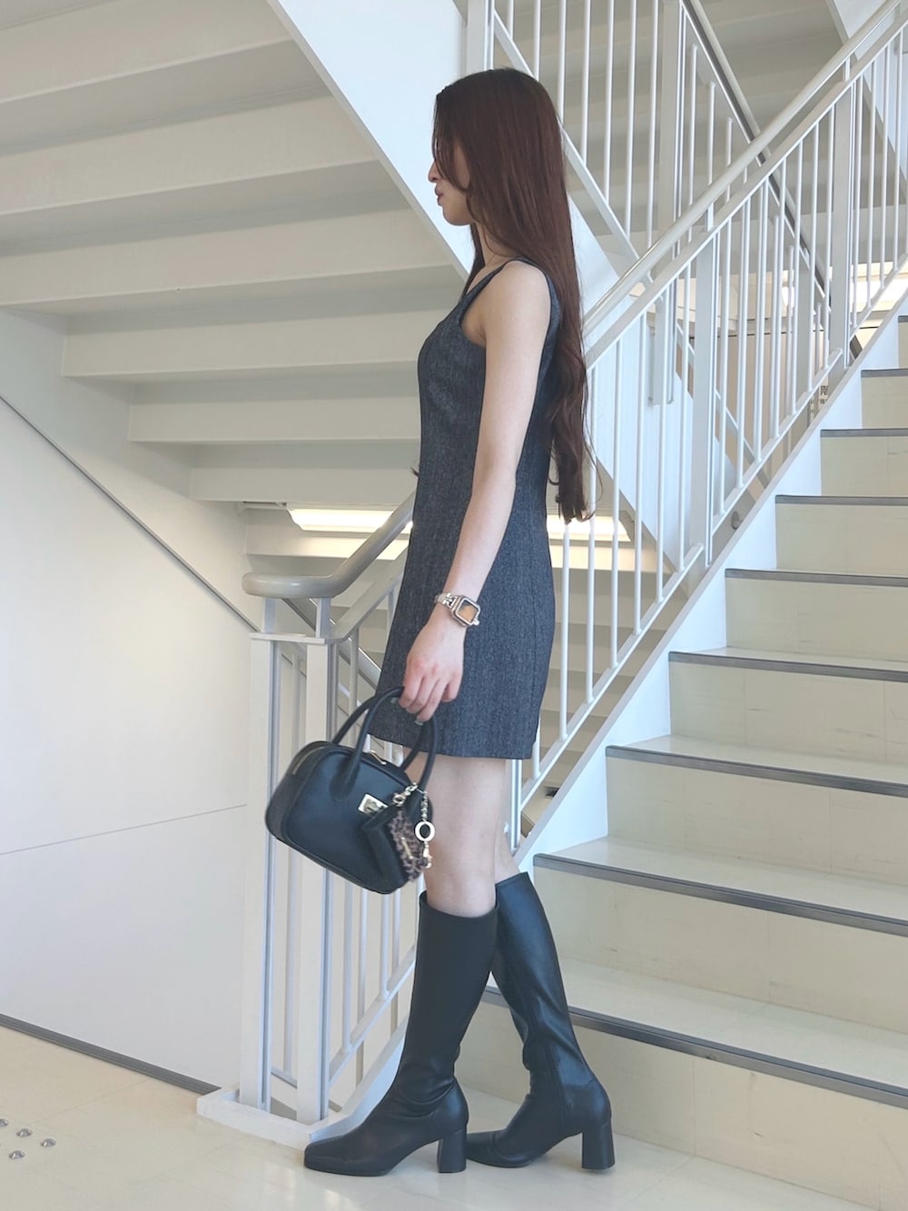 グレー系のワンピース、ブラック系のブーツ、ブラック系のハンドバッグを着用したレディースの夏コーディネートの2枚目の写真