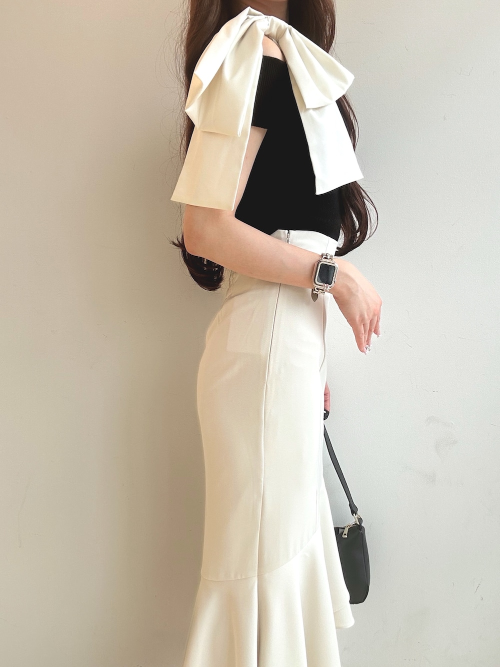 ブラック系のニット/セーター、ブラック系のハンドバッグ、ホワイト系のサンダルを着用したレディースの夏コーディネートの6枚目の写真