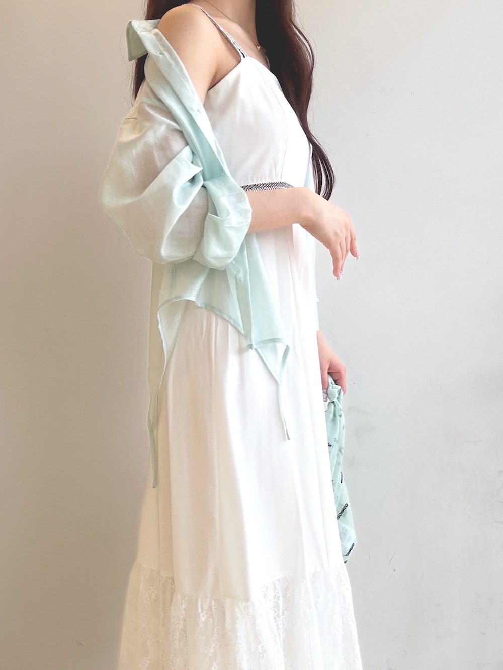 グリーン系のハンドバッグ、ホワイト系のワンピース、ブラウン系のサンダルを着用したレディースの夏コーディネートの6枚目の写真