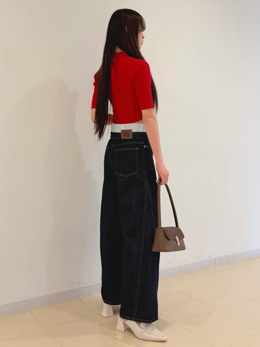 ブルー系のその他パンツ、レッド系のニット/セーター、ブラウン系のハンドバッグを着用したレディースの春コーディネートの2枚目の写真