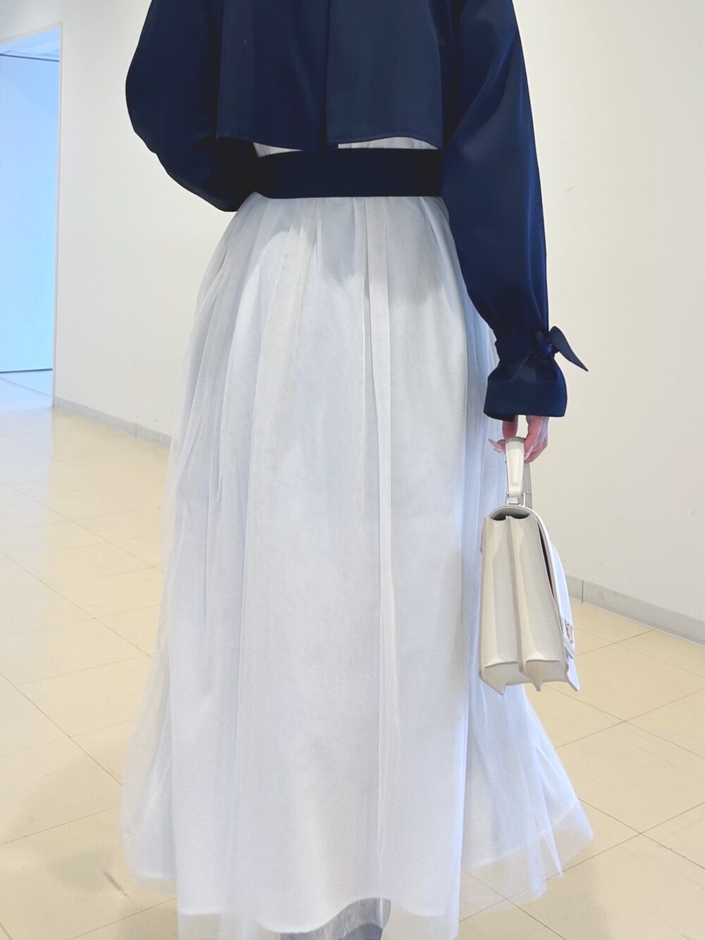 ブラック系のブーツ、ホワイト系のハンドバッグ、ホワイト系のニット/セーターを着用したレディースの春コーディネートの7枚目の写真