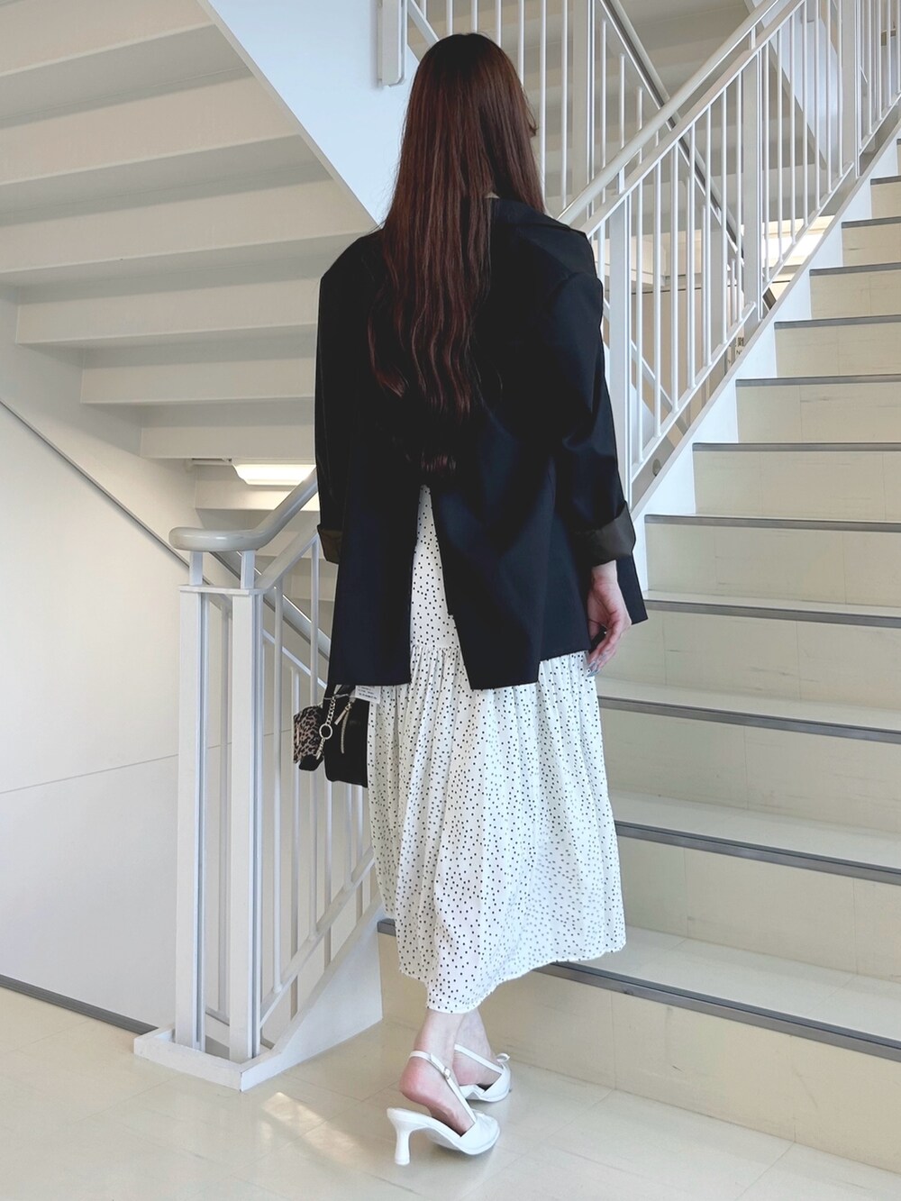 ブラック系のハンドバッグ、ホワイト系のパンプス、ブラウン系のテーラードジャケットを着用したレディースの秋コーディネートの4枚目の写真