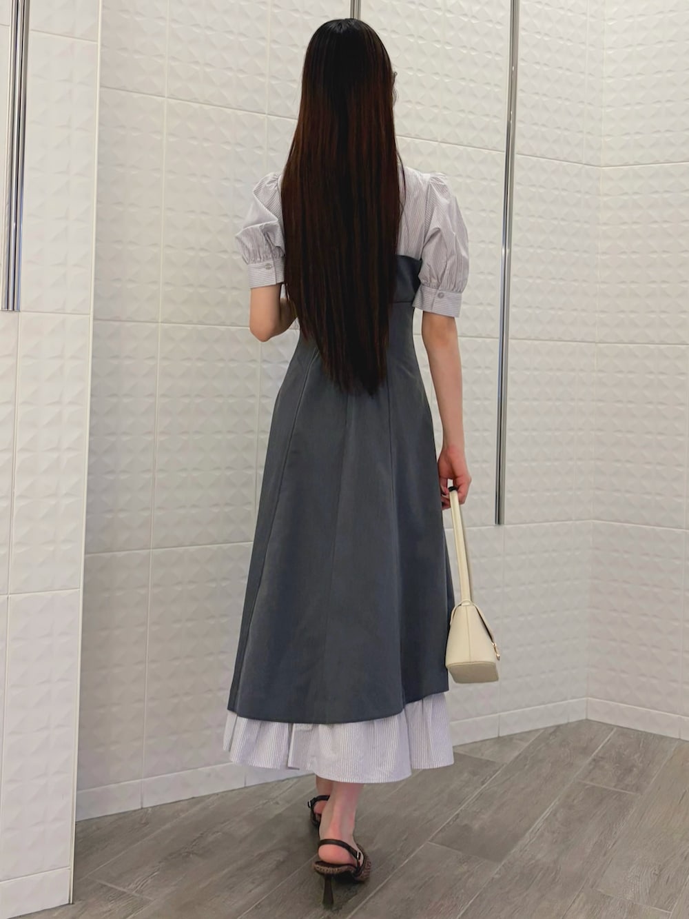 グレー系のワンピース、ホワイト系のハンドバッグ、ブラウン系のパンプスを着用したレディースの春コーディネートの3枚目の写真