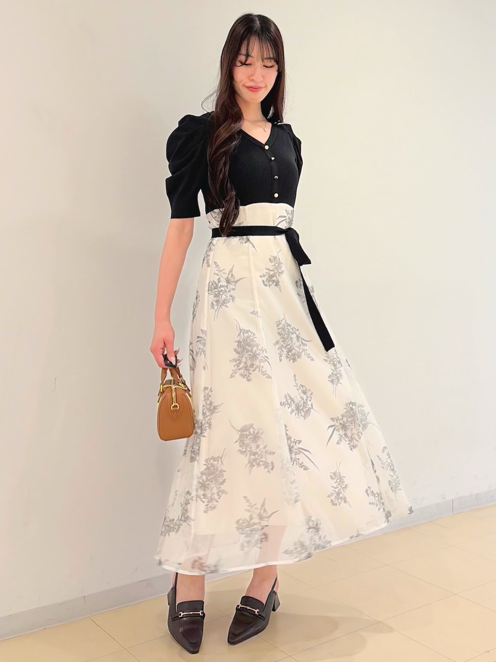 ブラック系のワンピース、ブラウン系のハンドバッグ、ブラウン系のパンプスを着用したレディースの春コーディネートの4枚目の写真