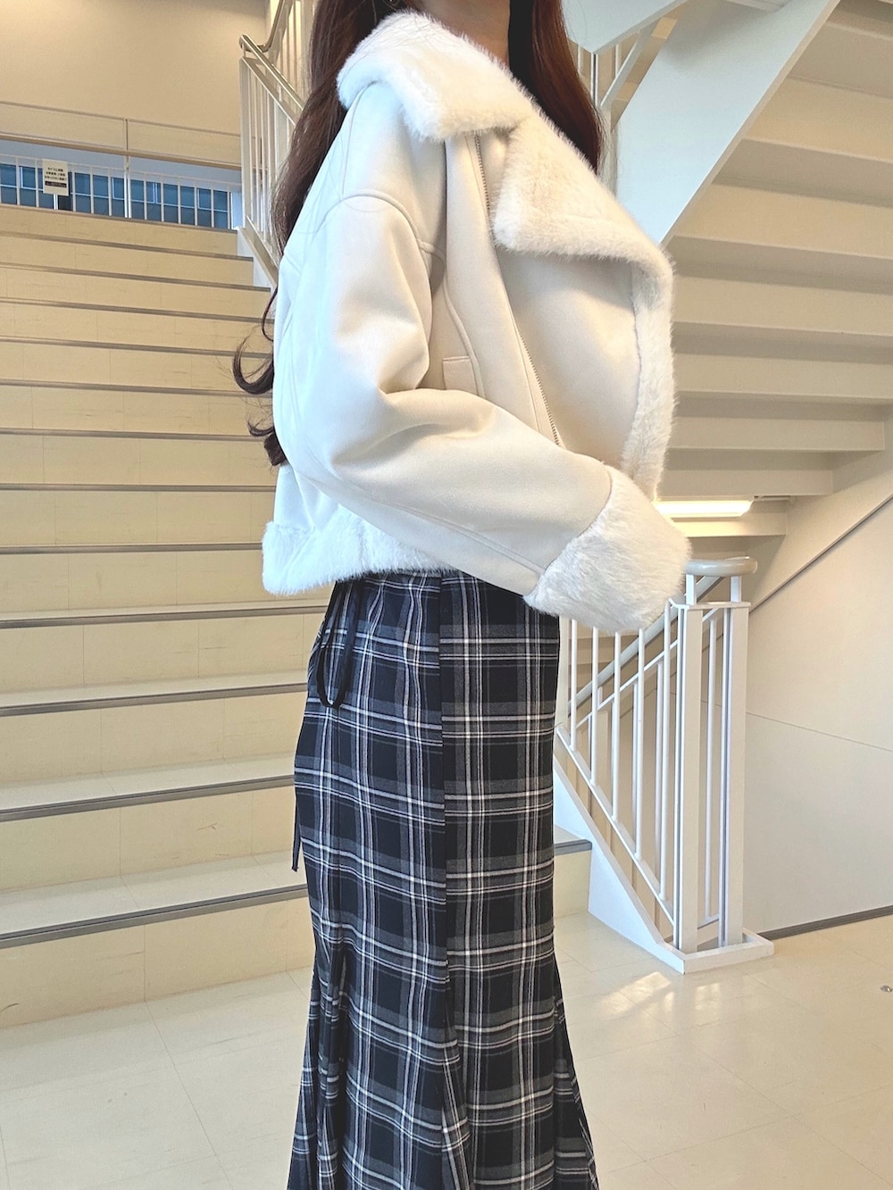 ブラック系のスカート、ホワイト系のムートンコート、ブラウン系のニット/セーターを着用したレディースの秋コーディネートの6枚目の写真