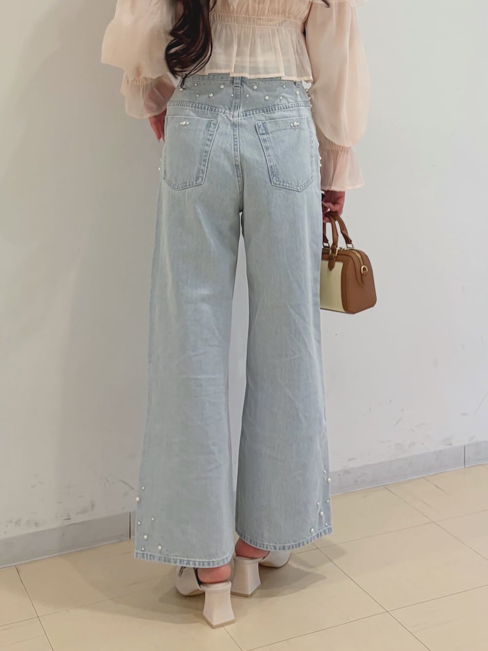 ピンク系のシャツ/ブラウス、ブルー系のデニムパンツ、ブラウン系のハンドバッグを着用したレディースの春コーディネートの6枚目の写真