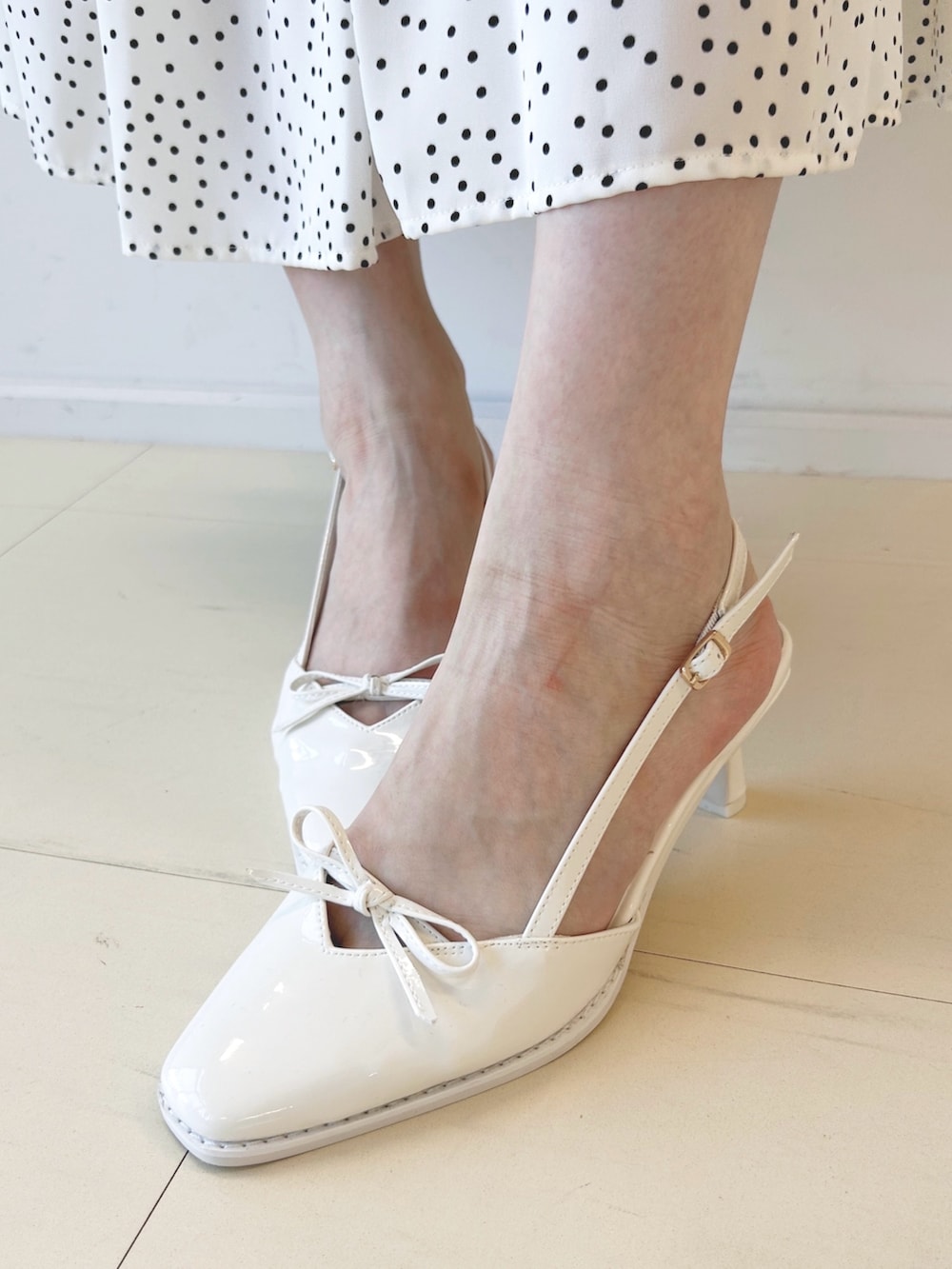 ホワイト系のパンプス、ブラック系のハンドバッグ、ホワイト系のワンピースを着用したレディースの秋コーディネートの7枚目の写真