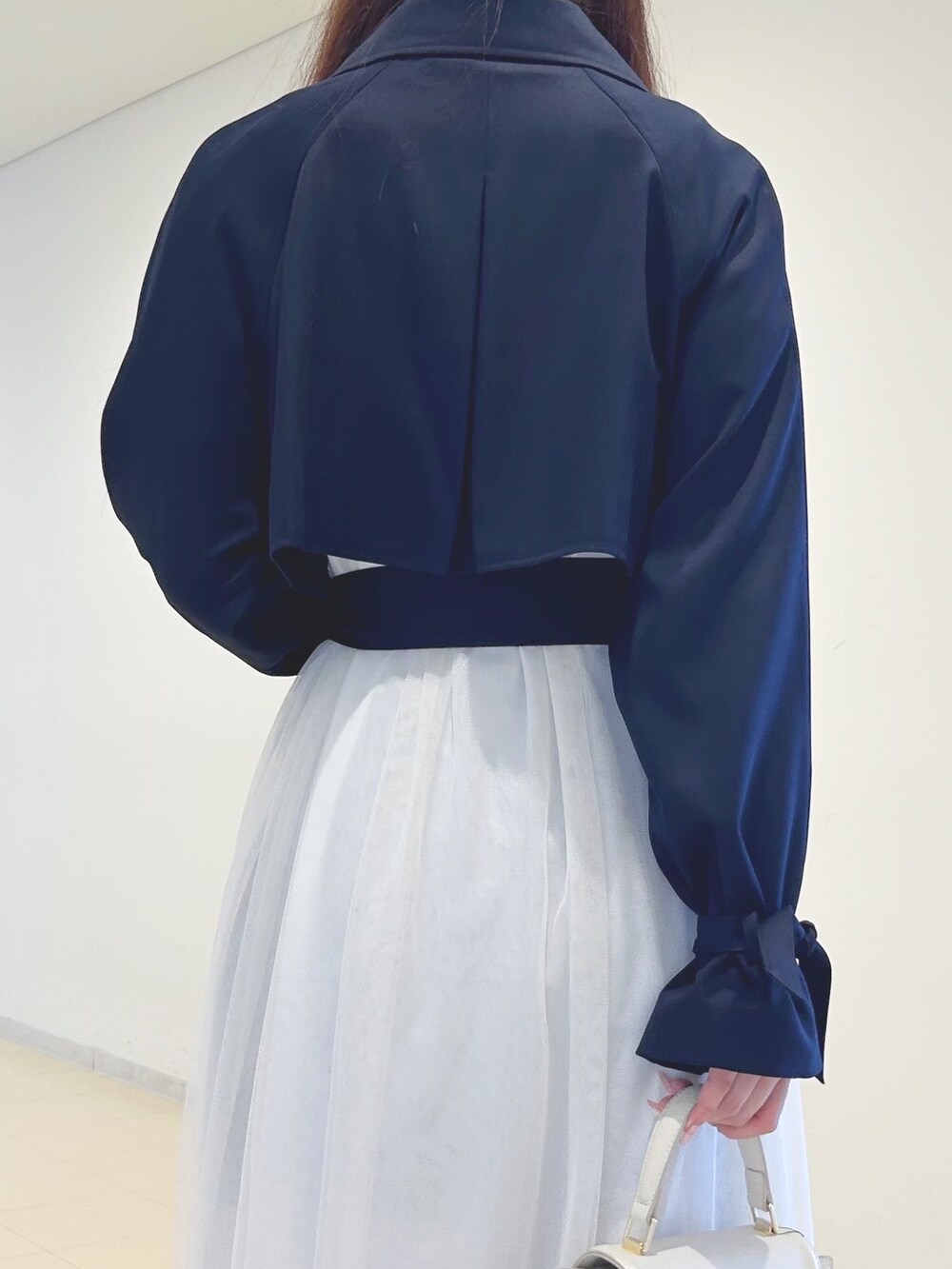 ブラック系のブーツ、ホワイト系のハンドバッグ、ホワイト系のニット/セーターを着用したレディースの春コーディネートの6枚目の写真