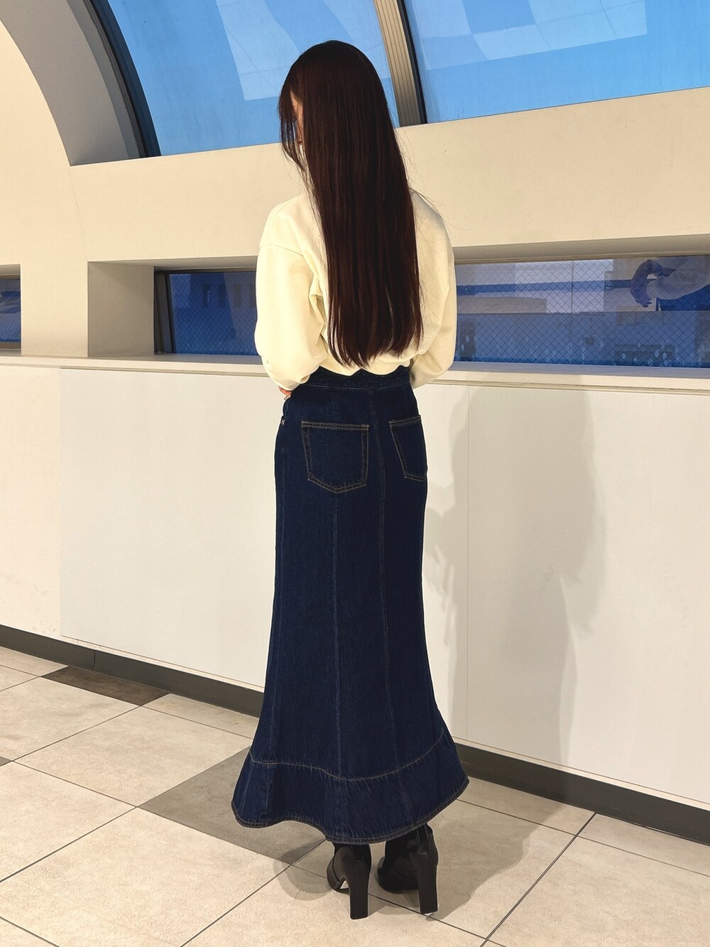 ブルー系のデニムスカート、ブラック系のブーツ、ホワイト系のスウェットを着用したレディースの冬コーディネートの4枚目の写真