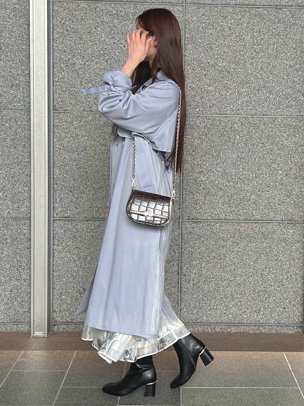 ブラック系のワンピース、ブルー系のトレンチコート、ブラウン系のハンドバッグを着用したレディースの秋コーディネートの4枚目の写真