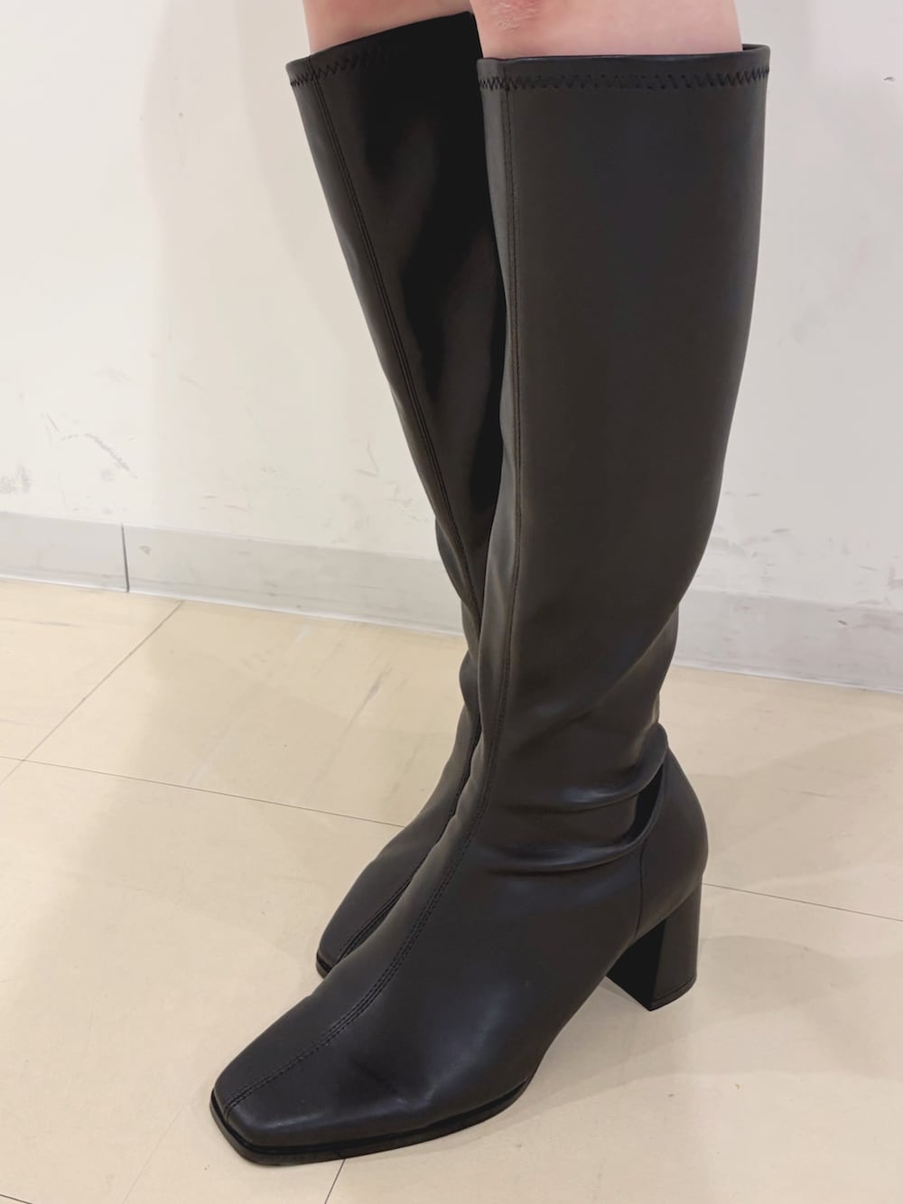 ホワイト系のスカート、ブラック系のブーツ、グレー系のニット/セーターを着用したレディースの冬コーディネートの7枚目の写真