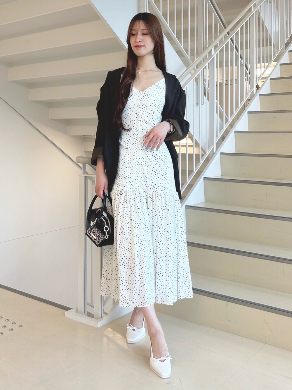 ブラック系のハンドバッグ、ホワイト系のパンプス、ブラウン系のテーラードジャケットを着用したレディースの秋コーディネートの3枚目の写真