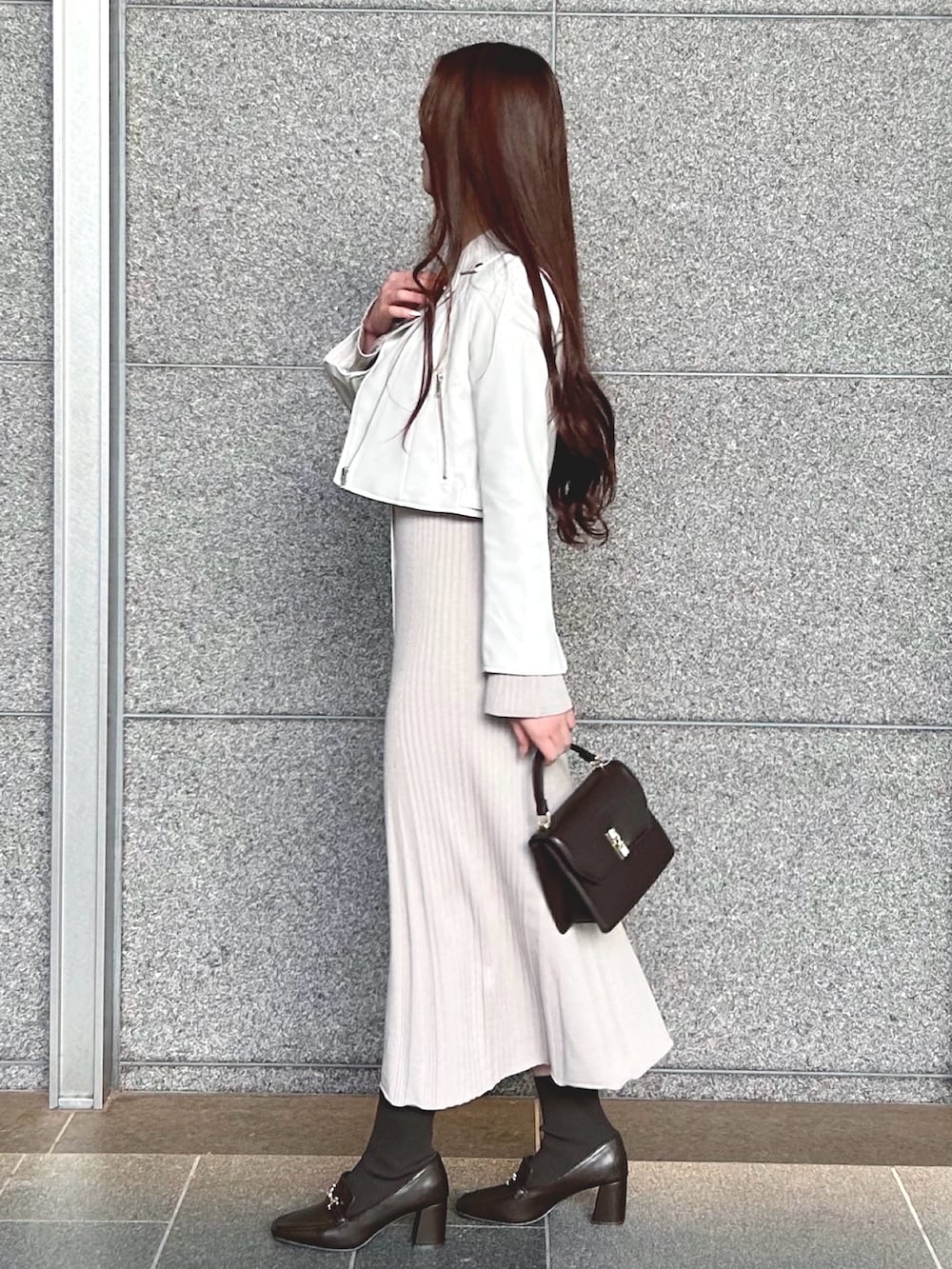 ブラウン系のハンドバッグ、ホワイト系のライダースジャケット、ピンク系のワンピースを着用したレディースの冬コーディネートの2枚目の写真