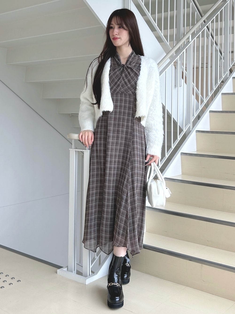 ブラウン系のワンピース、ホワイト系のハンドバッグ、ブラック系のブーツを着用したレディースの秋コーディネートの3枚目の写真