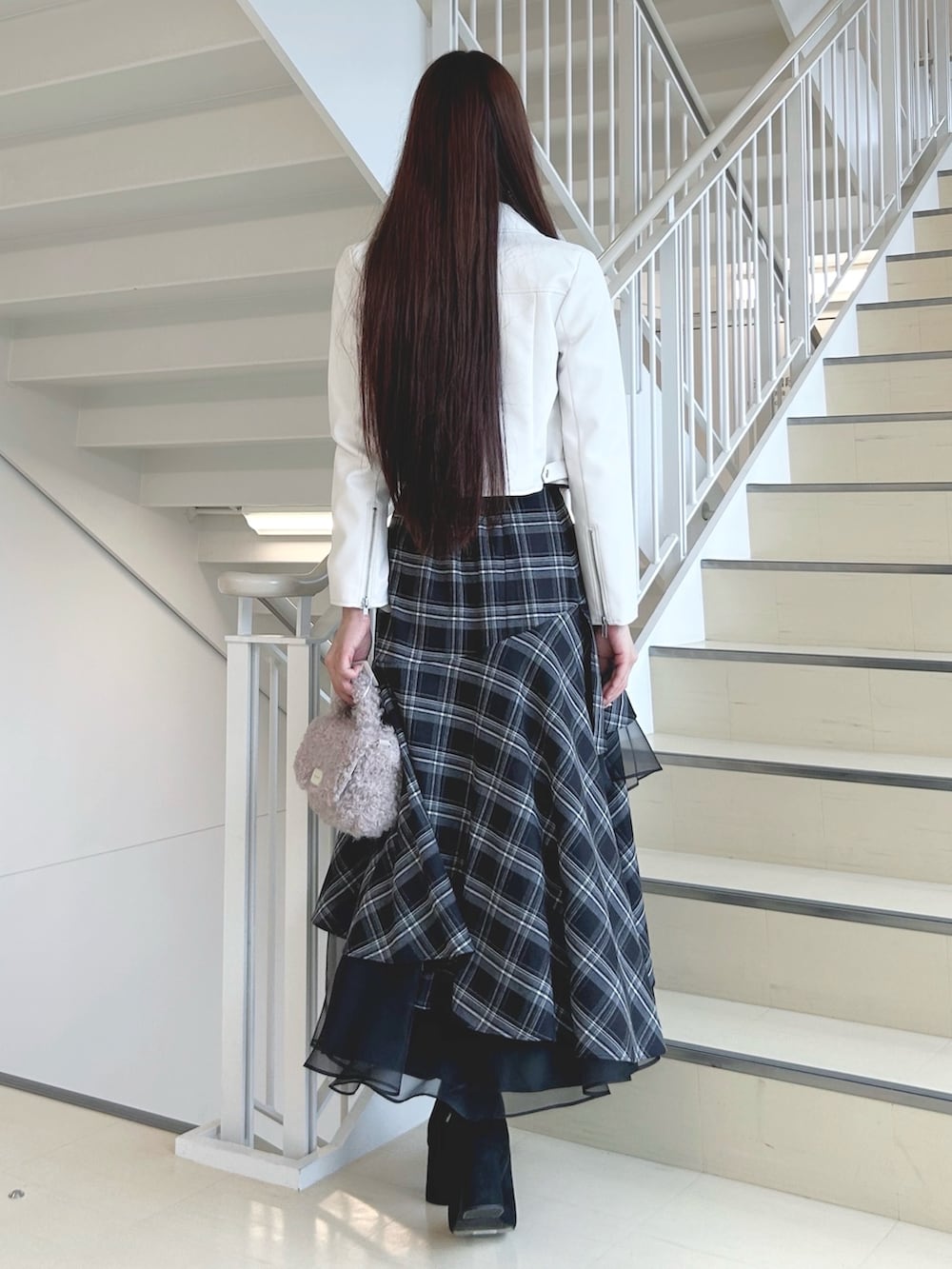 ブラック系のブーツ、ブラック系のスカート、ピンク系のハンドバッグを着用したレディースの秋コーディネートの4枚目の写真