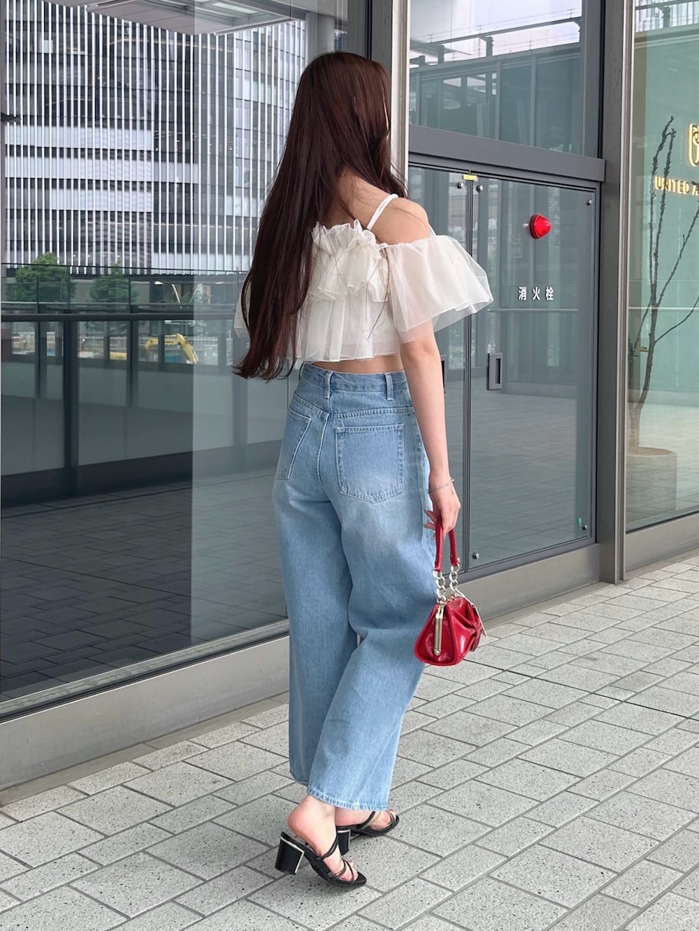 レッド系のハンドバッグ、ホワイト系のシャツ/ブラウス、ブルー系のデニムパンツを着用したレディースの春コーディネートの3枚目の写真