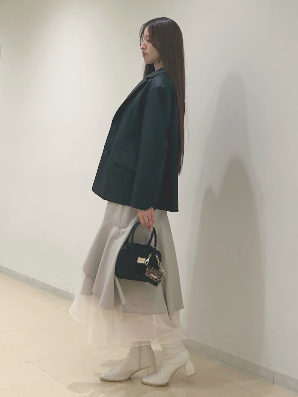 ベージュ系のスカート、グレー系のニット/セーター、ブラック系のハンドバッグを着用したレディースの秋コーディネートの2枚目の写真