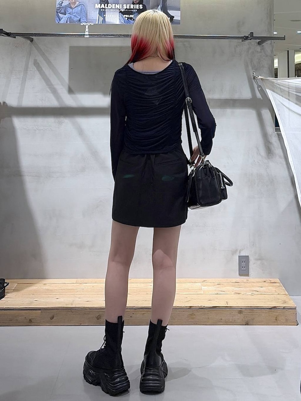 ブラック系のブーツ、ブラック系のスカート、ブラック系のショルダーバッグを着用したレディースの春コーディネートの6枚目の写真