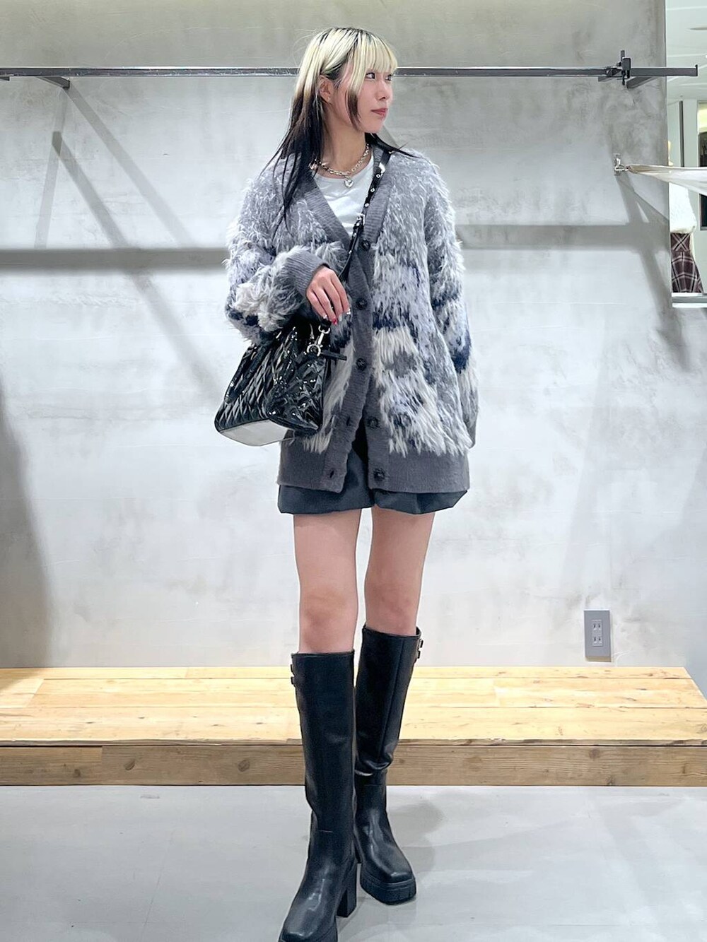 ホワイト系のTシャツ/カットソー、グレー系のカーディガン/ボレロ、ブラック系のブーツを着用したレディースの冬コーディネートの2枚目の写真