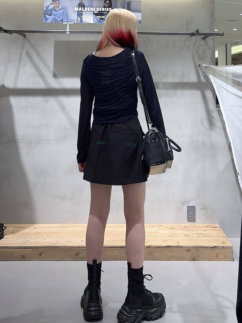 ブラック系のブーツ、ブラック系のスカート、ブラック系のショルダーバッグを着用したレディースの春コーディネートの5枚目の写真