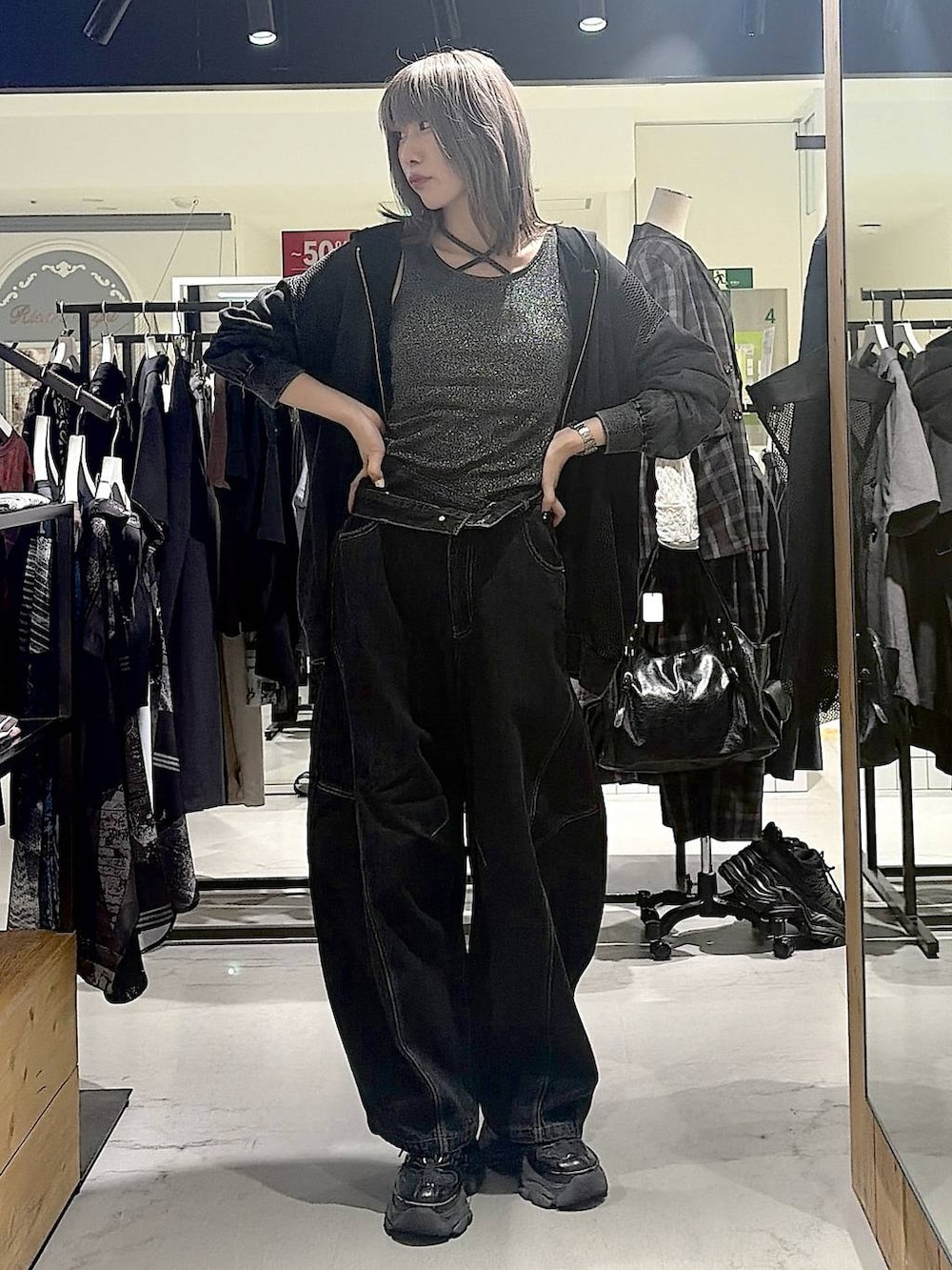 グレー系のパーカー、ブラック系のデニムパンツ、ブラック系のスニーカーを着用したレディースの秋コーディネートの7枚目の写真