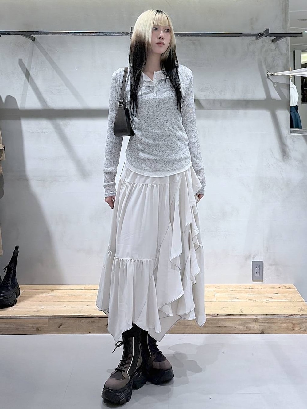 ブラウン系のブーツ、ベージュ系のスカート、ブラウン系のハンドバッグを着用したレディースの春コーディネートの2枚目の写真