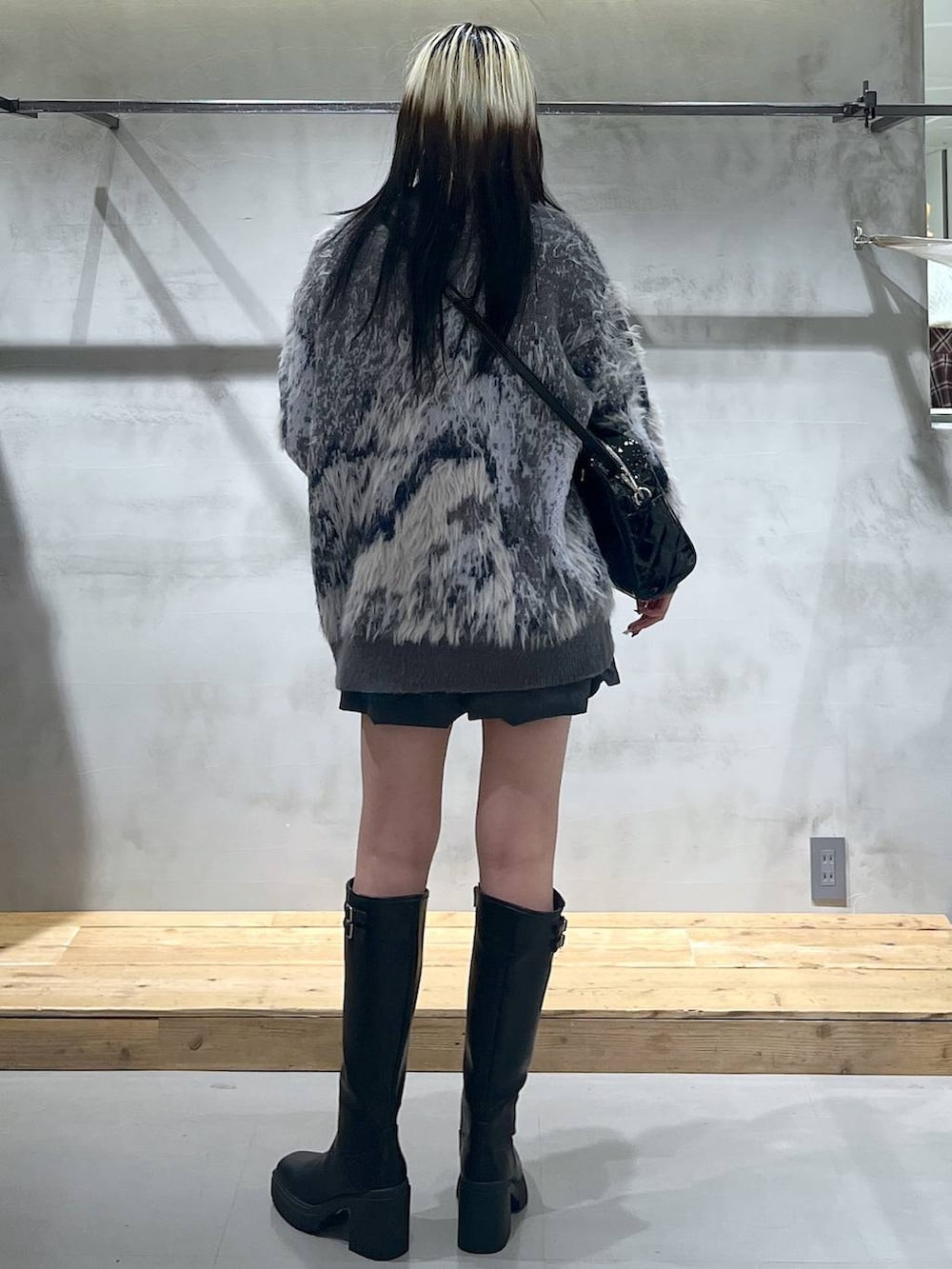 ホワイト系のTシャツ/カットソー、グレー系のカーディガン/ボレロ、ブラック系のブーツを着用したレディースの冬コーディネートの4枚目の写真