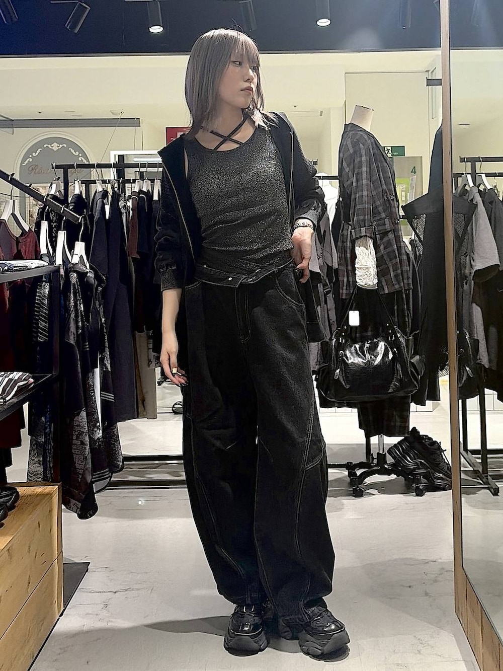 グレー系のパーカー、ブラック系のデニムパンツ、ブラック系のスニーカーを着用したレディースの秋コーディネートの3枚目の写真