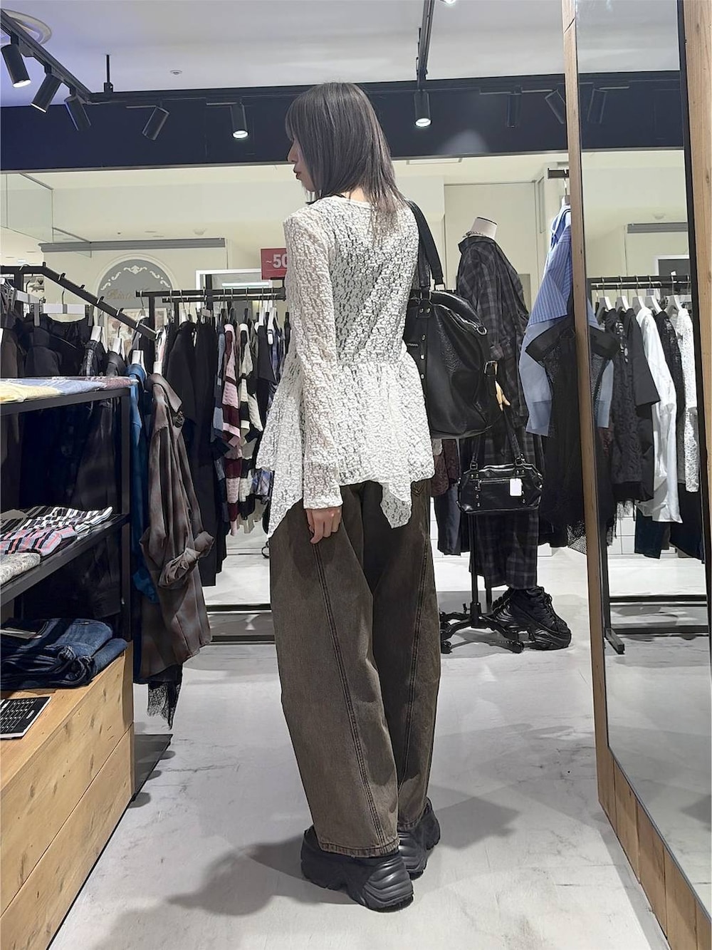 ブラック系のボストンバッグ、ブラウン系のデニムパンツ、ブラック系のスニーカーを着用したレディースの秋コーディネートの9枚目の写真