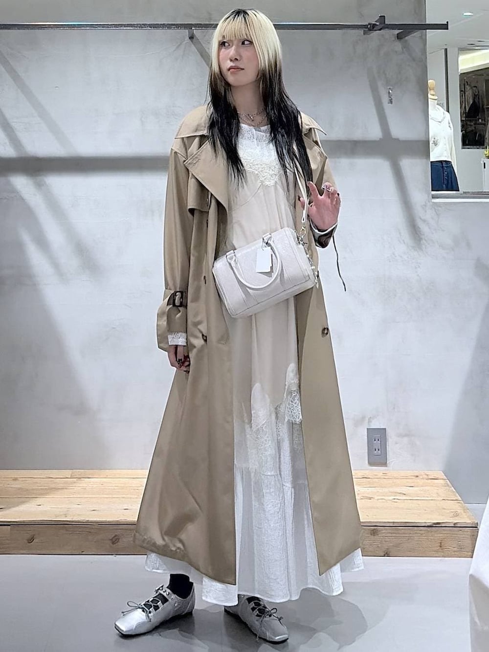 ベージュ系のトレンチコート、ホワイト系のボストンバッグ、シルバー系のスニーカーを着用したレディースの春コーディネートの3枚目の写真
