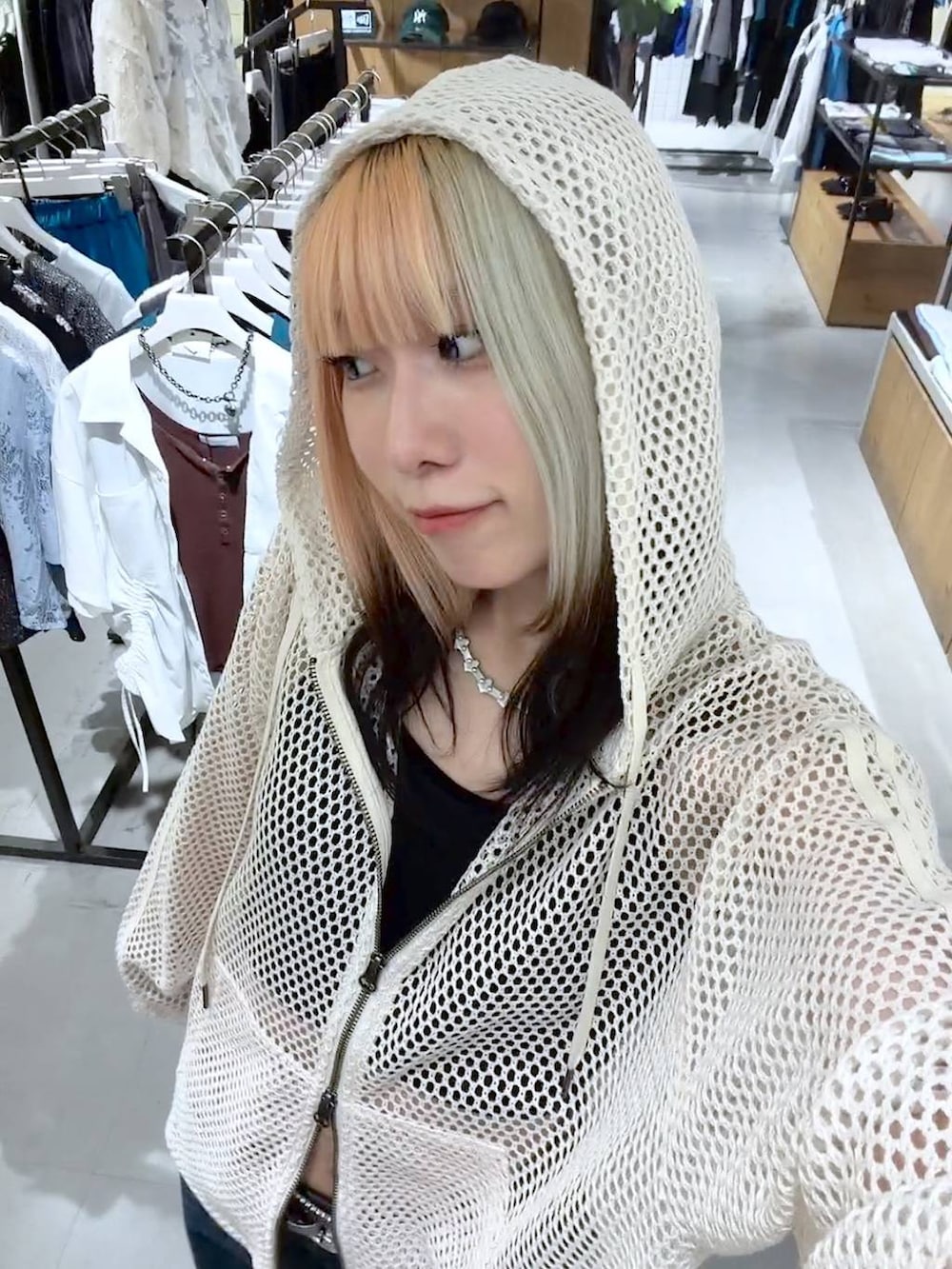 ホワイト系のパーカー、ブラック系のキャミソール、ブルー系のデニムパンツを着用したレディースの夏コーディネートの4枚目の写真