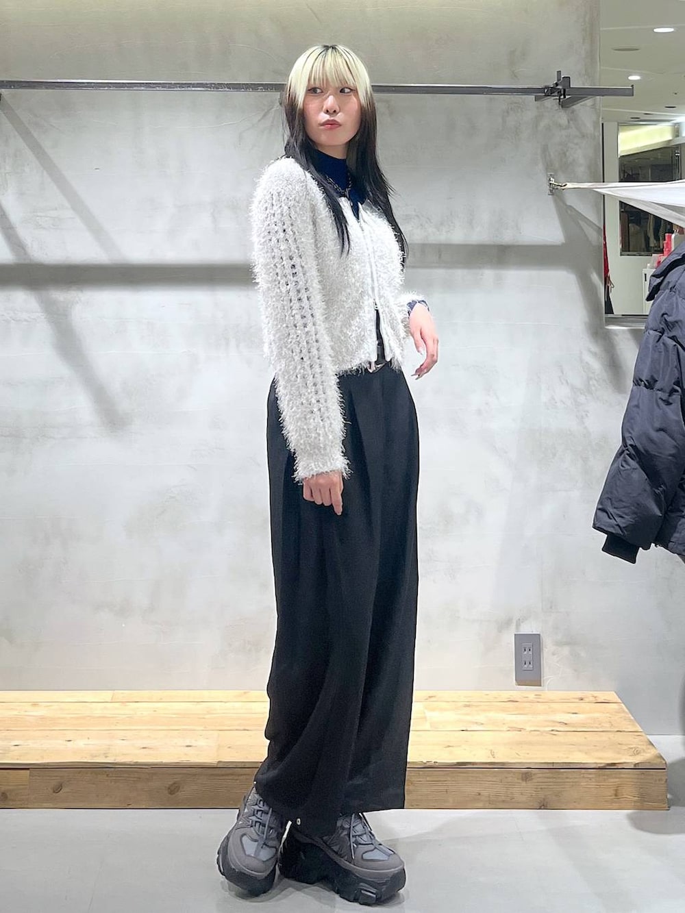 グレー系のスニーカー、ホワイト系のカーディガン/ボレロ、ブラック系のスラックスを着用したレディースの秋コーディネートの2枚目の写真