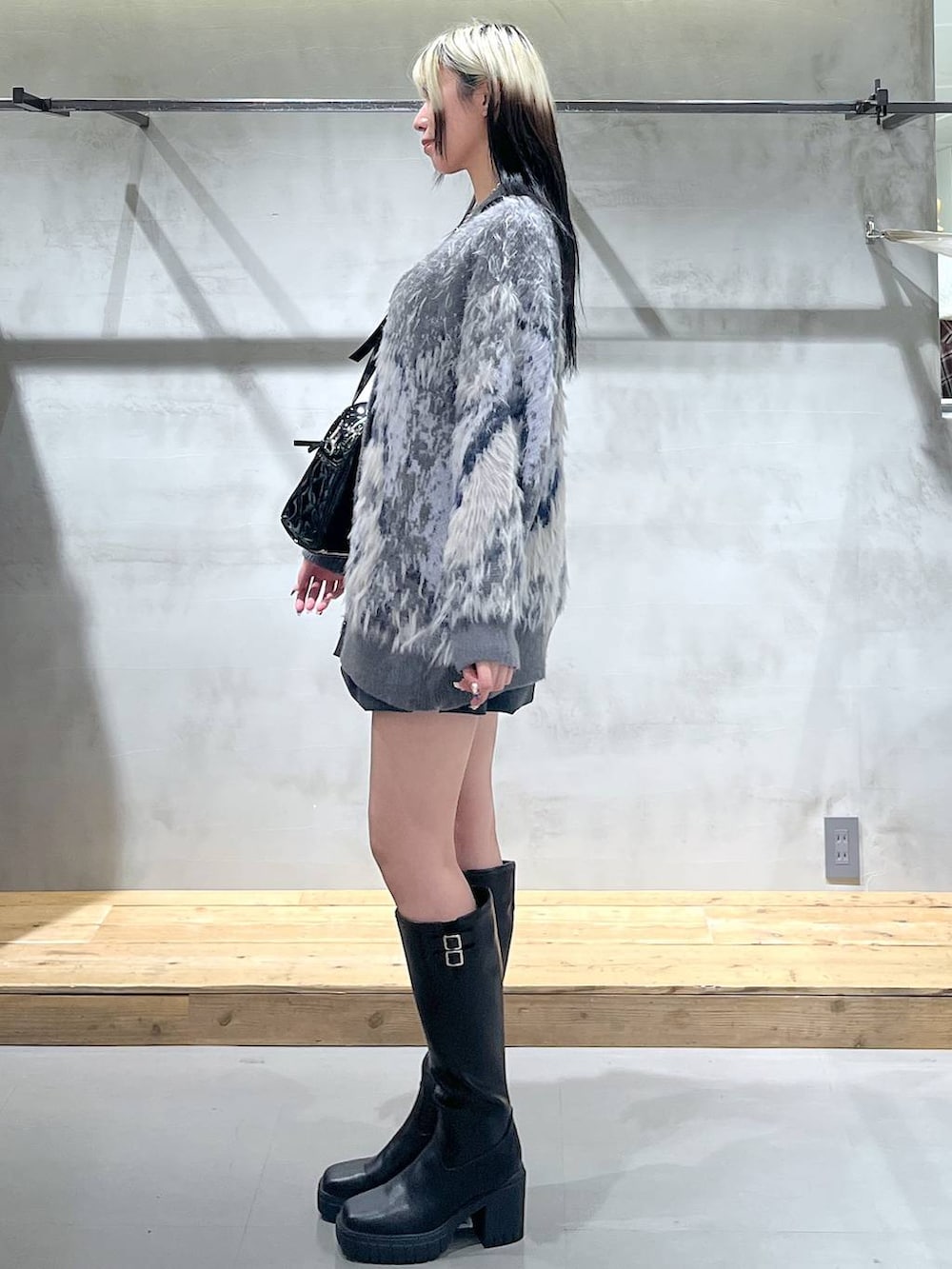 ホワイト系のTシャツ/カットソー、グレー系のカーディガン/ボレロ、ブラック系のブーツを着用したレディースの冬コーディネートの3枚目の写真