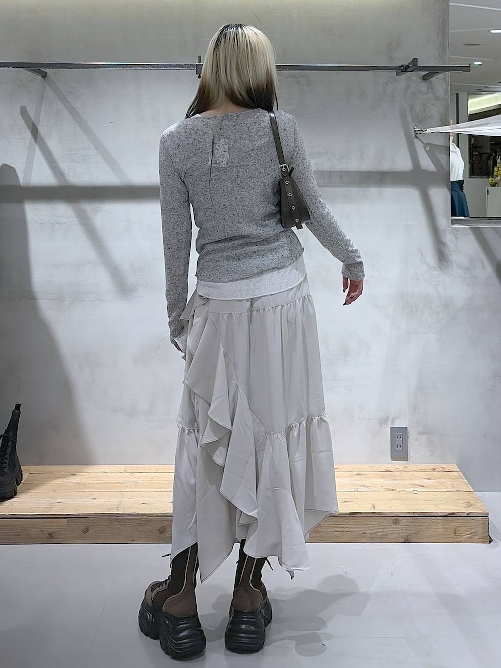 ブラウン系のブーツ、ベージュ系のスカート、ブラウン系のハンドバッグを着用したレディースの春コーディネートの6枚目の写真