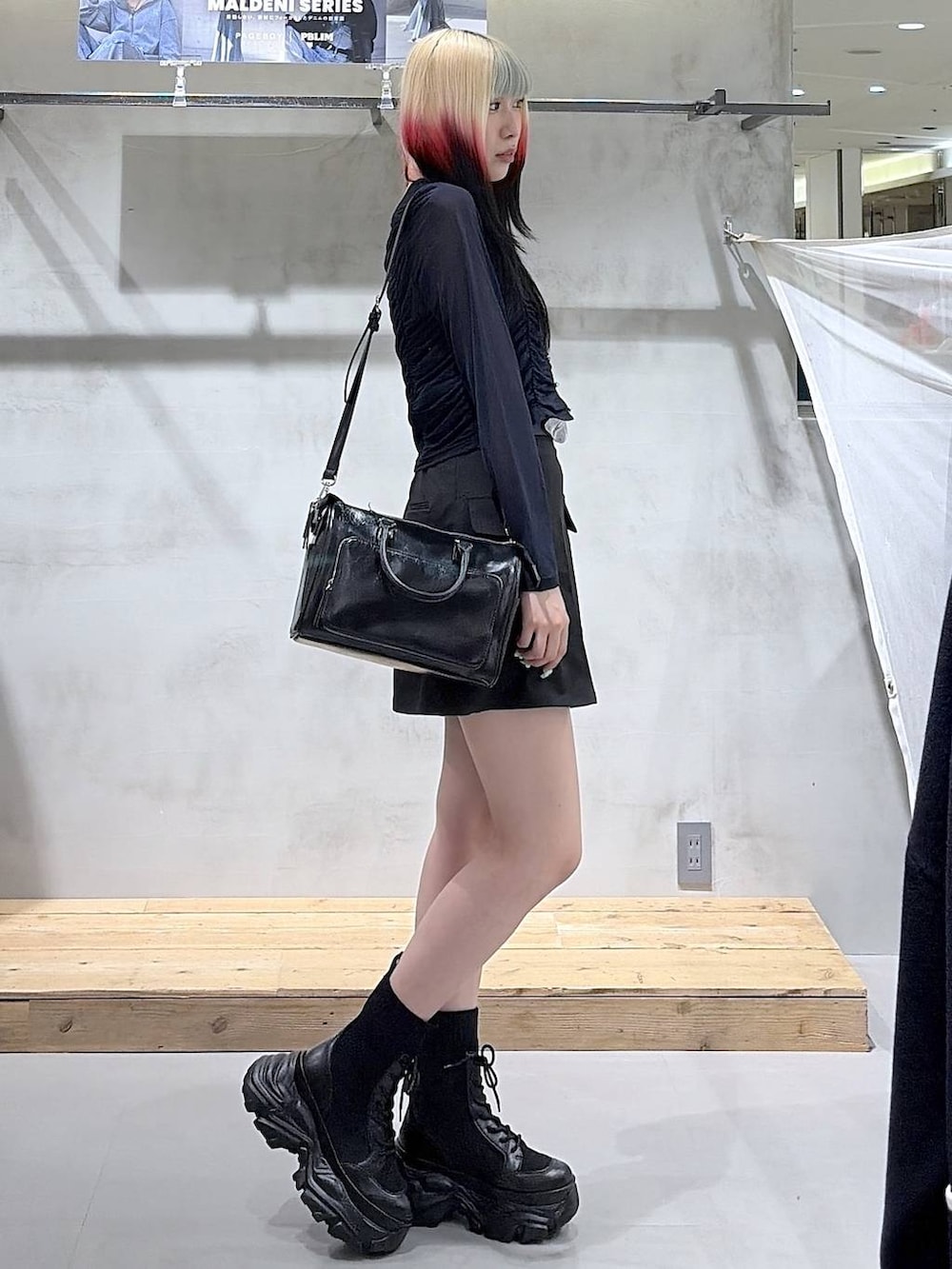 ブラック系のブーツ、ブラック系のスカート、ブラック系のショルダーバッグを着用したレディースの春コーディネートの4枚目の写真