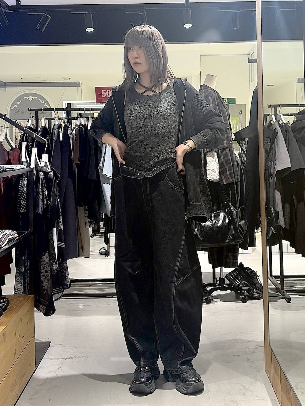 グレー系のパーカー、ブラック系のデニムパンツ、ブラック系のスニーカーを着用したレディースの秋コーディネートの5枚目の写真