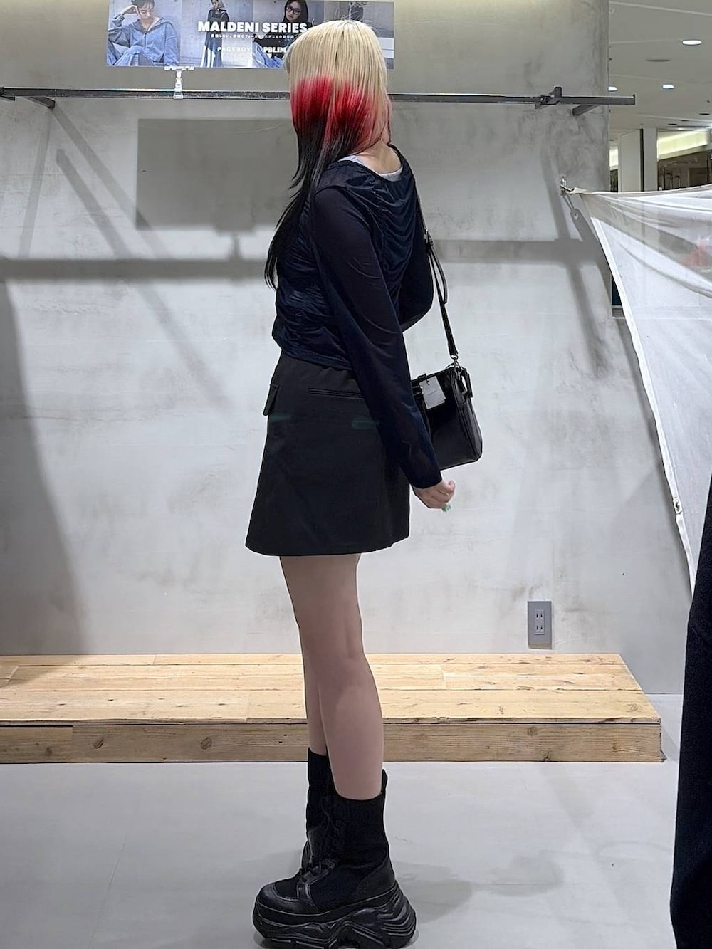 ブラック系のブーツ、ブラック系のスカート、ブラック系のショルダーバッグを着用したレディースの春コーディネートの7枚目の写真