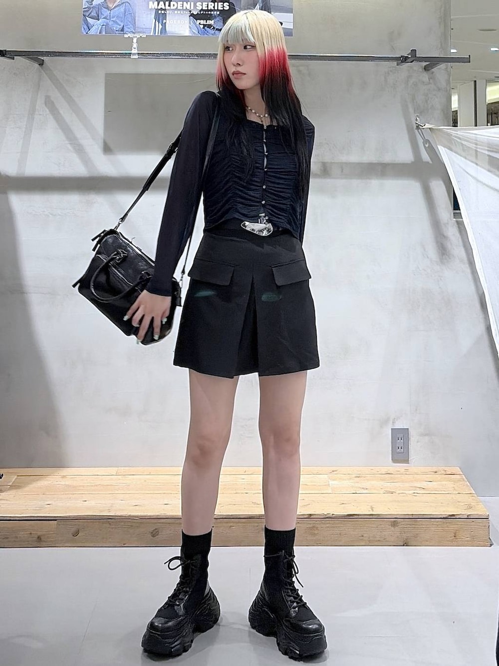 ブラック系のブーツ、ブラック系のスカート、ブラック系のショルダーバッグを着用したレディースの春コーディネートの8枚目の写真