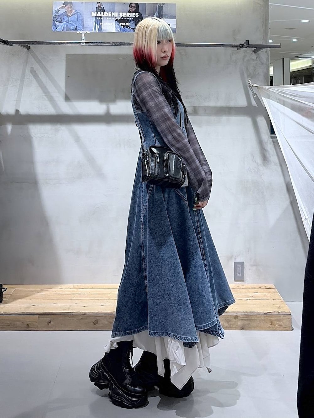 ブラック系のブーツ、ベージュ系のスカート、ブラック系のショルダーバッグを着用したレディースの春コーディネートの3枚目の写真