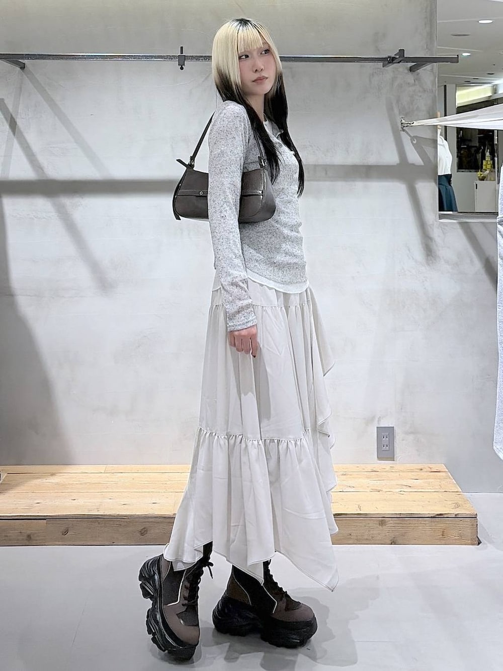 ブラウン系のブーツ、ベージュ系のスカート、ブラウン系のハンドバッグを着用したレディースの春コーディネートの3枚目の写真