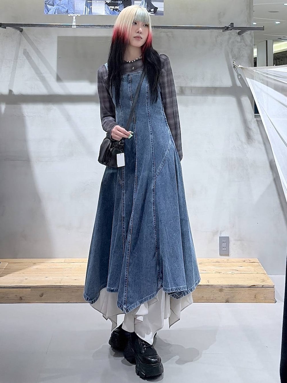 ブラック系のブーツ、ベージュ系のスカート、ブラック系のショルダーバッグを着用したレディースの春コーディネートの2枚目の写真