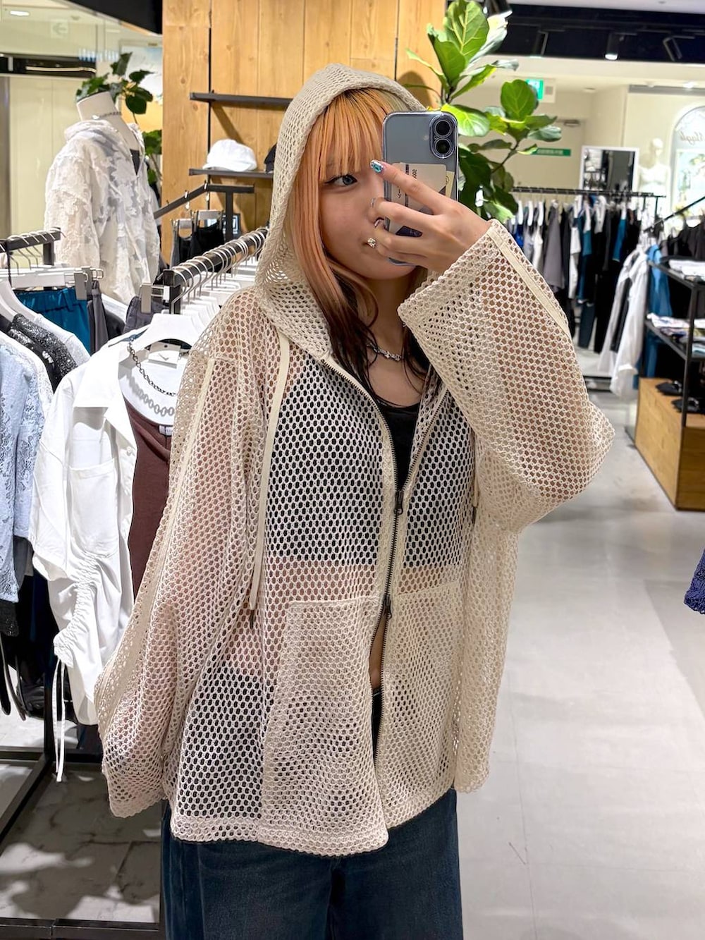 ホワイト系のパーカー、ブラック系のキャミソール、ブルー系のデニムパンツを着用したレディースの夏コーディネートの6枚目の写真