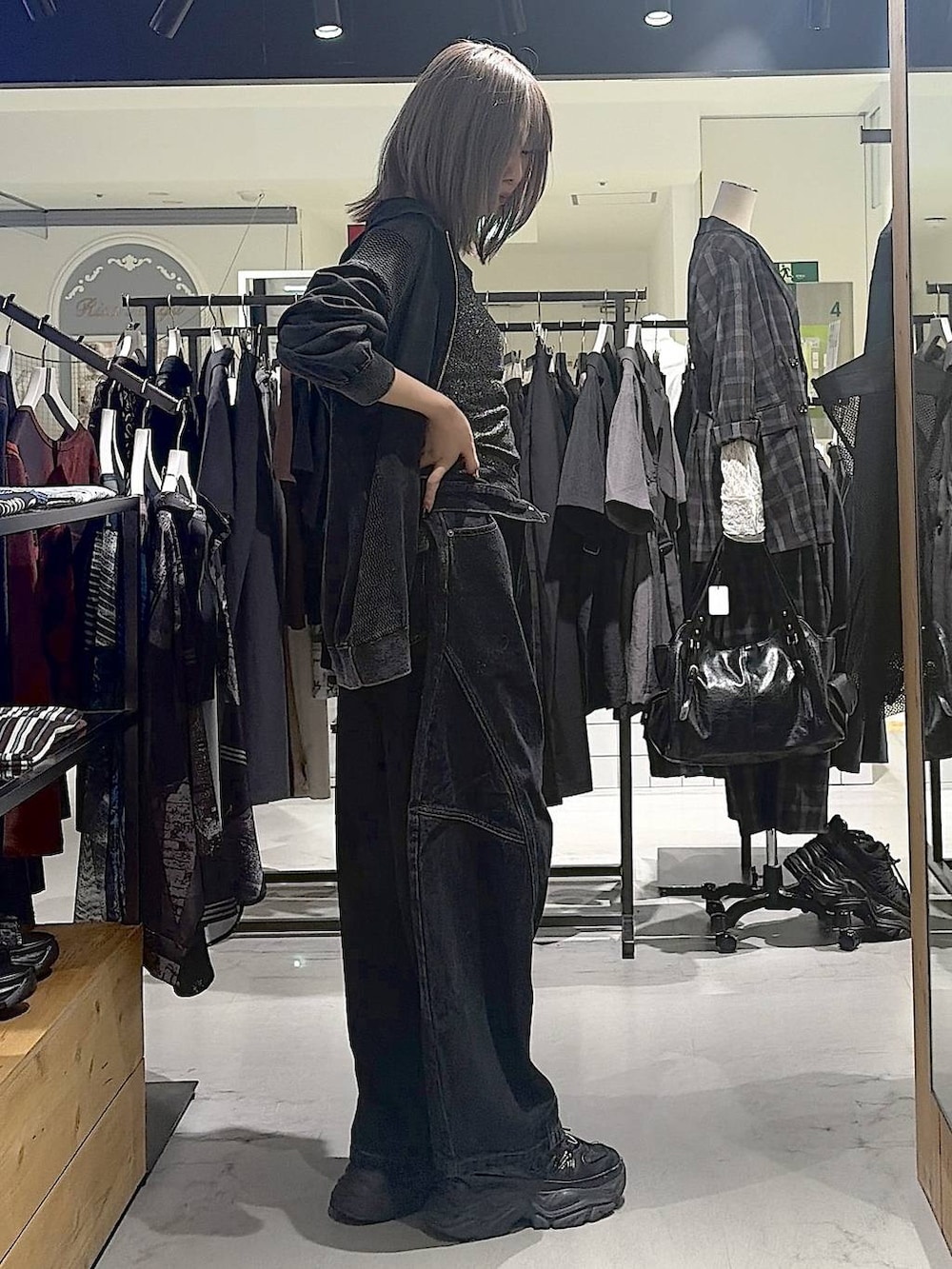 グレー系のパーカー、ブラック系のデニムパンツ、ブラック系のスニーカーを着用したレディースの秋コーディネートの6枚目の写真