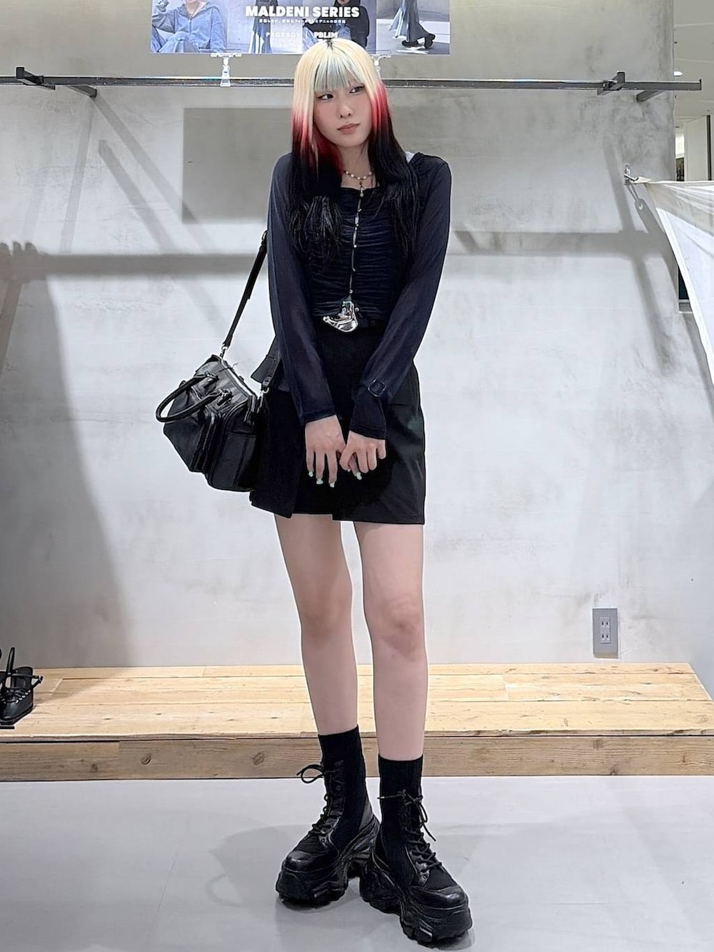 ブラック系のブーツ、ブラック系のスカート、ブラック系のショルダーバッグを着用したレディースの春コーディネートの2枚目の写真