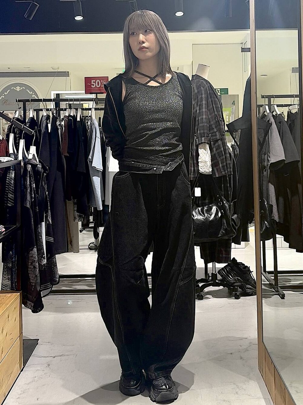グレー系のパーカー、ブラック系のデニムパンツ、ブラック系のスニーカーを着用したレディースの秋コーディネートの2枚目の写真