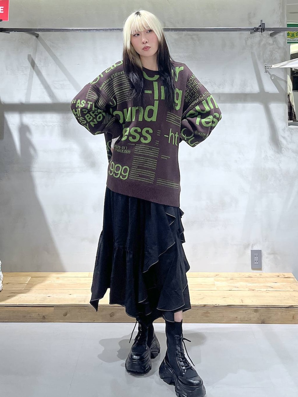 ブラック系のブーツ、ホワイト系のTシャツ/カットソー、ブラック系のスカートを着用したレディースの冬コーディネートの2枚目の写真