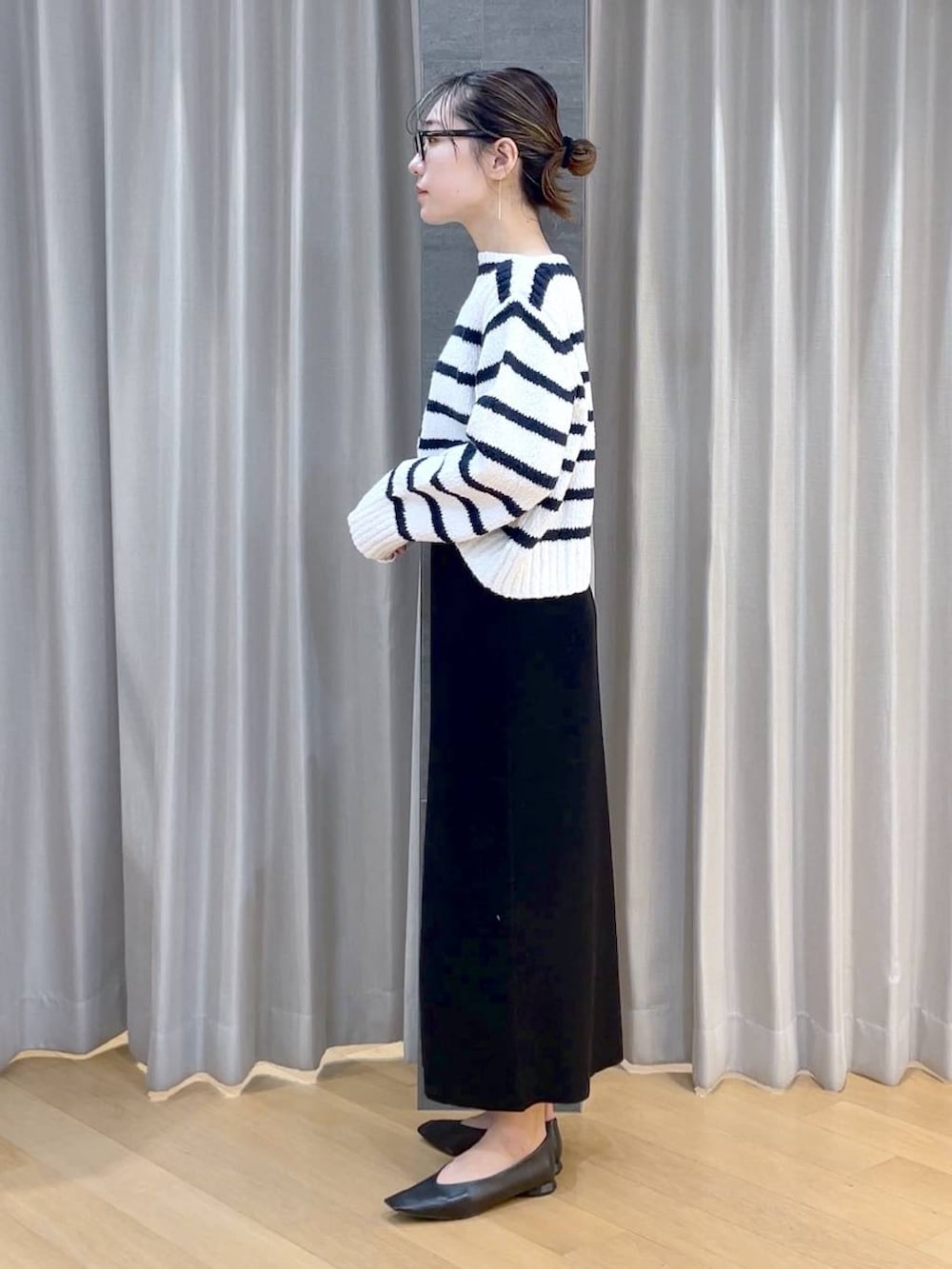 ブラック系のパンプス、ブラック系のスカート、ホワイト系のニット/セーターを着用したレディースの冬コーディネートの3枚目の写真