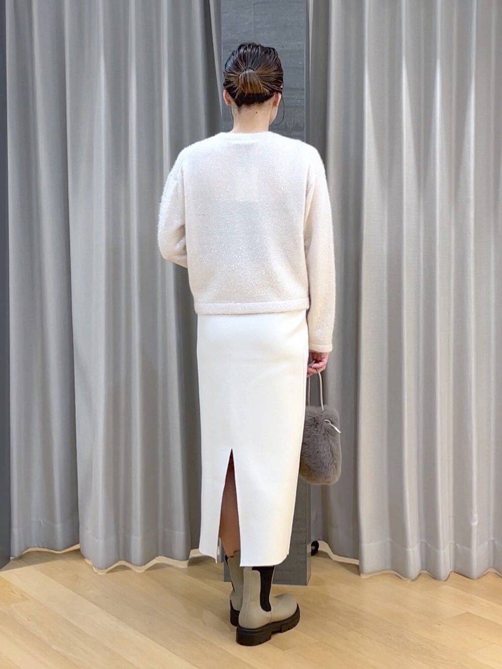 ベージュ系のブーツ、ホワイト系のニット/セーター、ベージュ系のショルダーバッグを着用したレディースの冬コーディネートの5枚目の写真